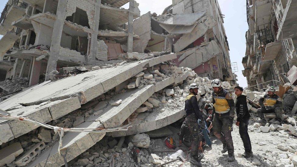 Rescue workers from the Syria Civil Defence, also known as the White Helmets, search the rubble of a collapsed building following an explosion in the opposition-held town of Jisr al-Shughour (24 April 2019)