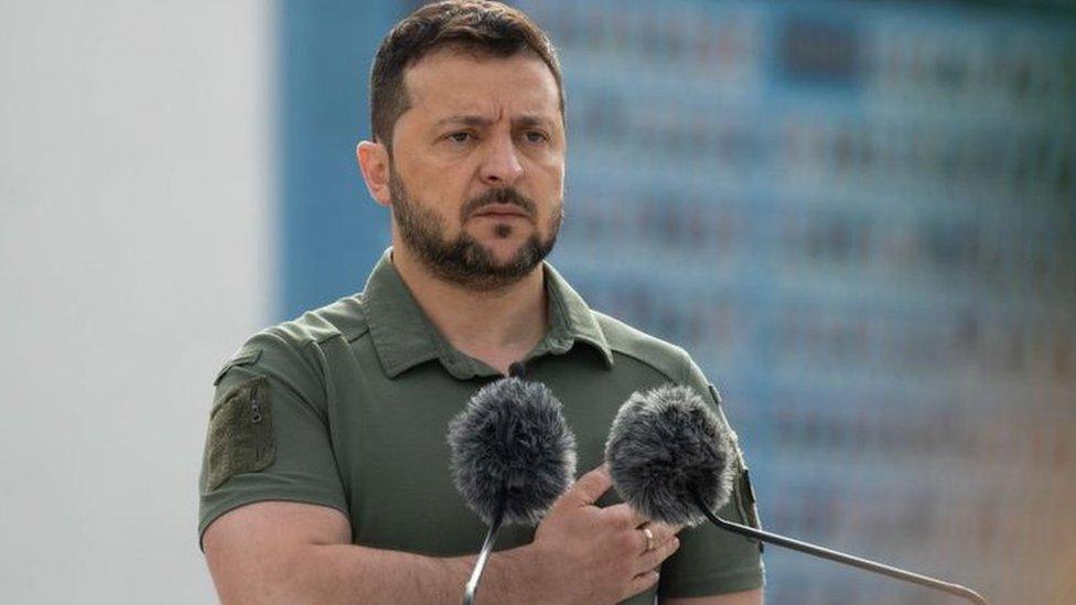 Volodymyr Zelensky standing behind a podium