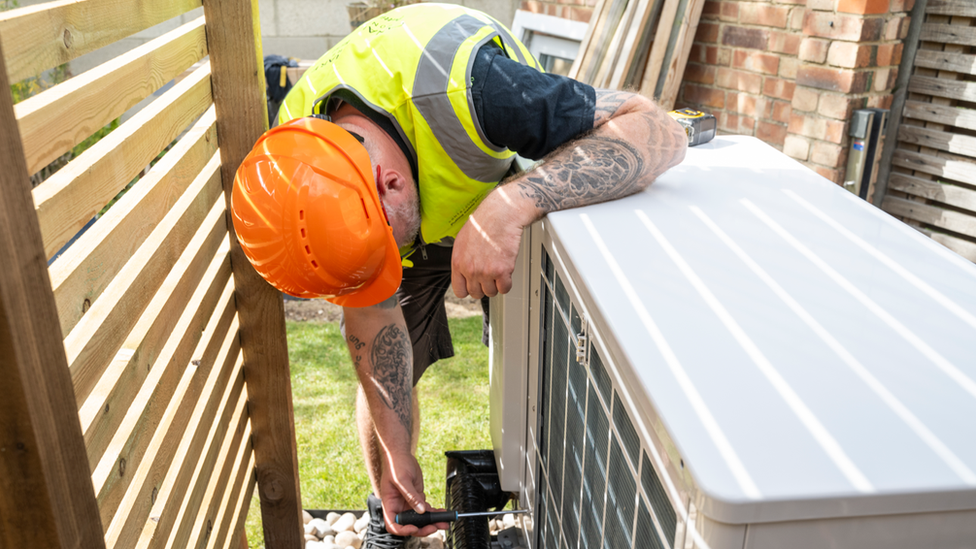 A man installing a heat pump in a garden