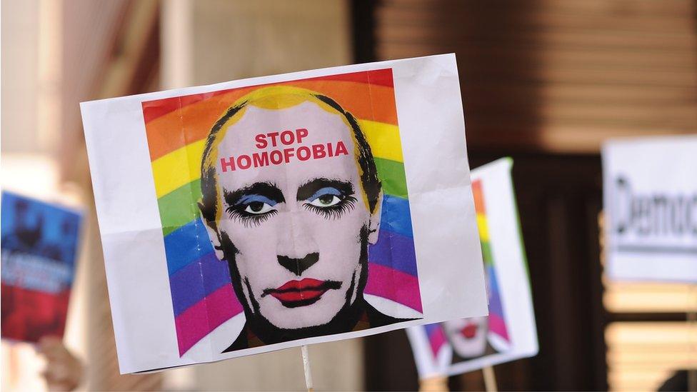 A protestor holds up an image representing Russian President Vladimir Putin wearing lipstick