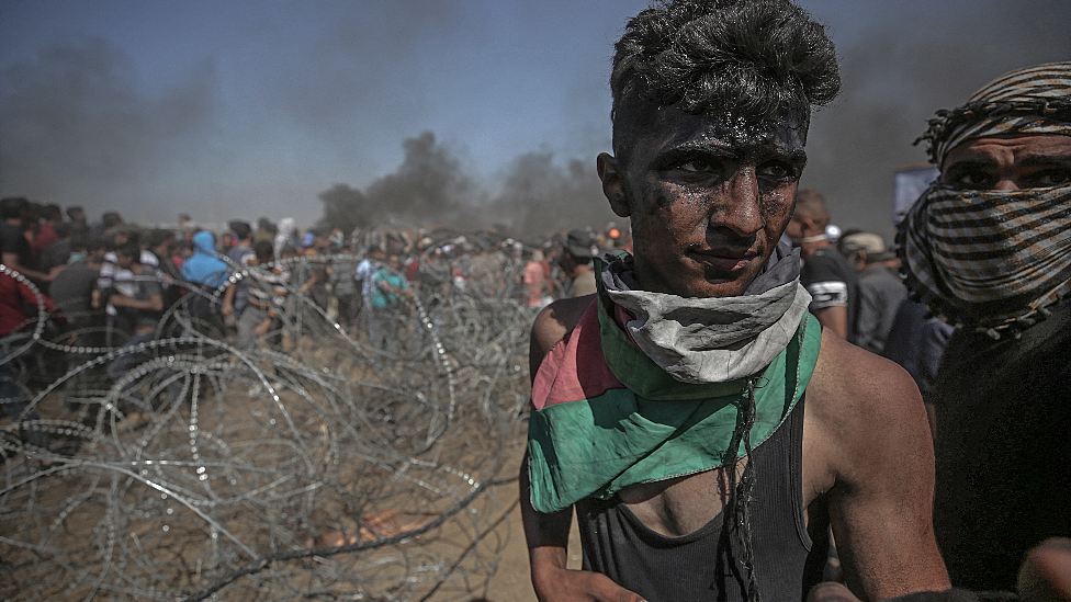 Palestinians protesters pulling barbed wire fence installed by Israeli army along the border during clashes after protests near the border with Israel in the east of Gaza Strip