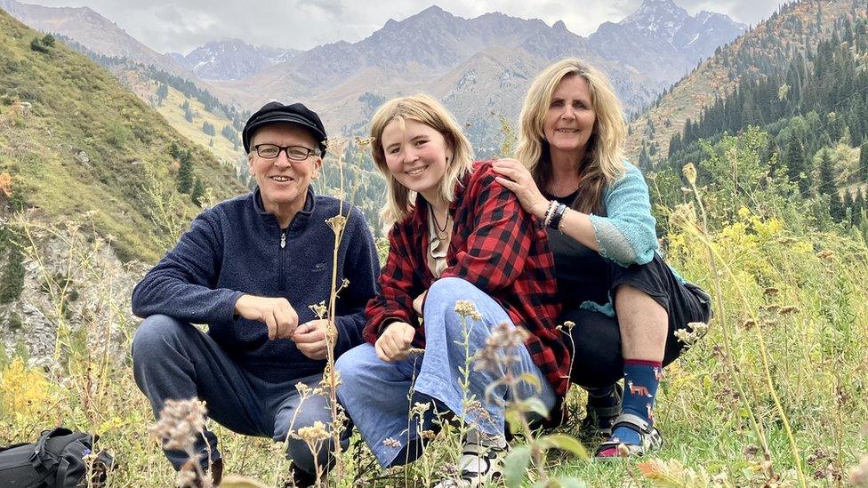 Family crouching with mountains in the background