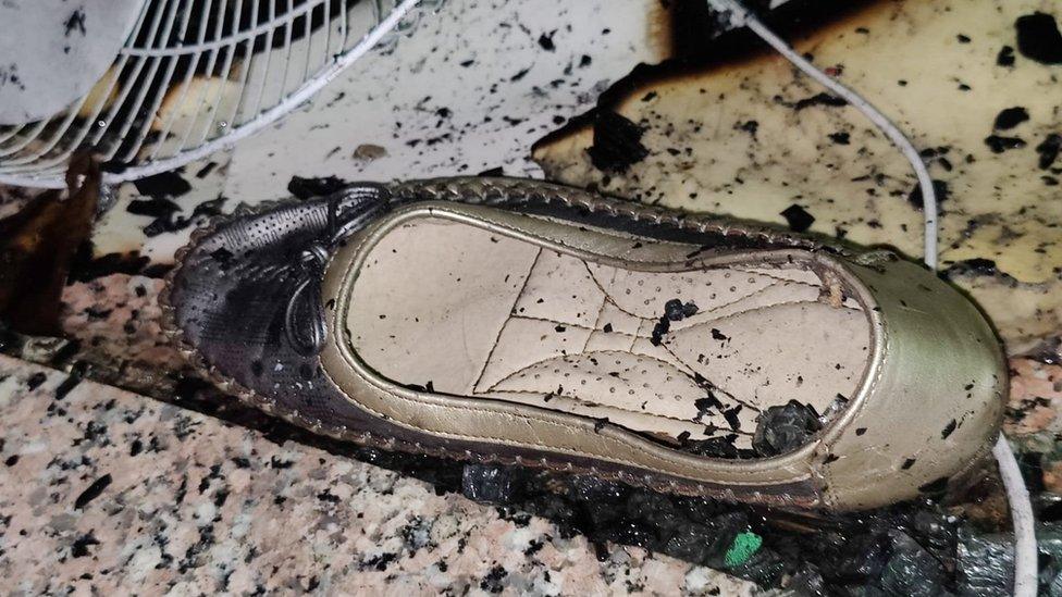 Women's shoes lie outside the charred building