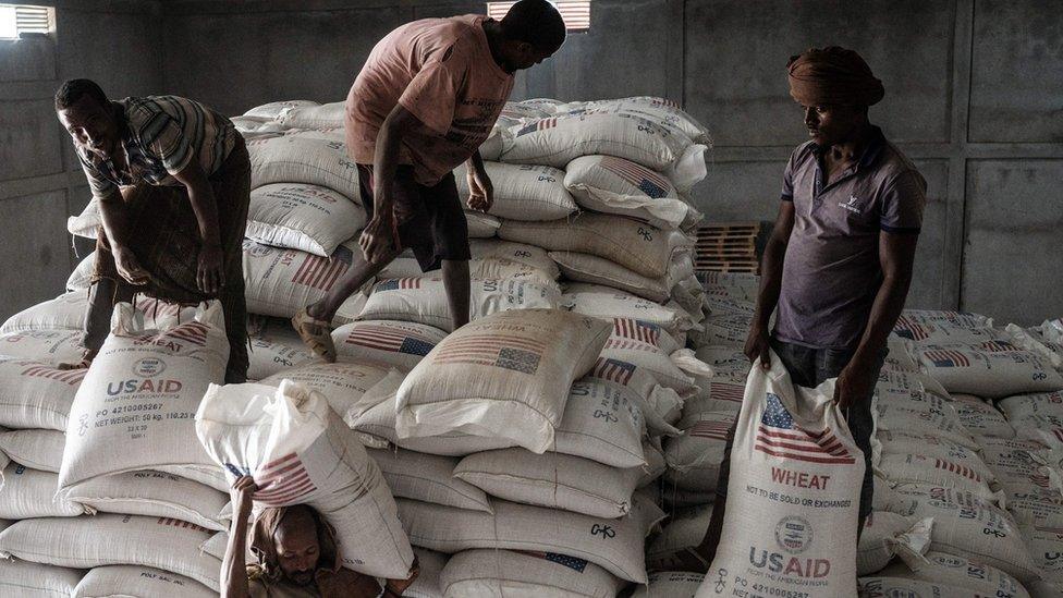 Men carrying bags of wheat from the US international development agency in a warehouse in Mekelle, Tigray