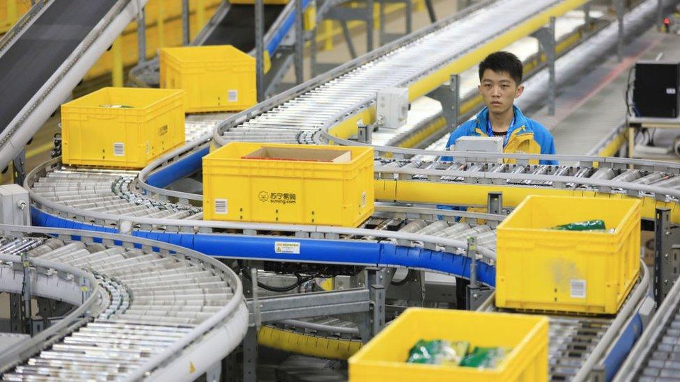 Man next to conveyor belt in Alibaba fulfilment centre.