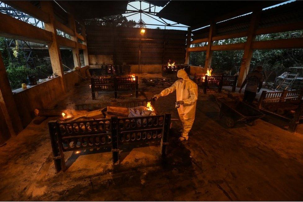 Relatives and municipal workers wearing personal protective equipment (PPE) perform the last rites for COVID-19 victims during their funeral at a cremation ground in Vasai, on the outskirts of Mumbai, India, 13 April 2021.