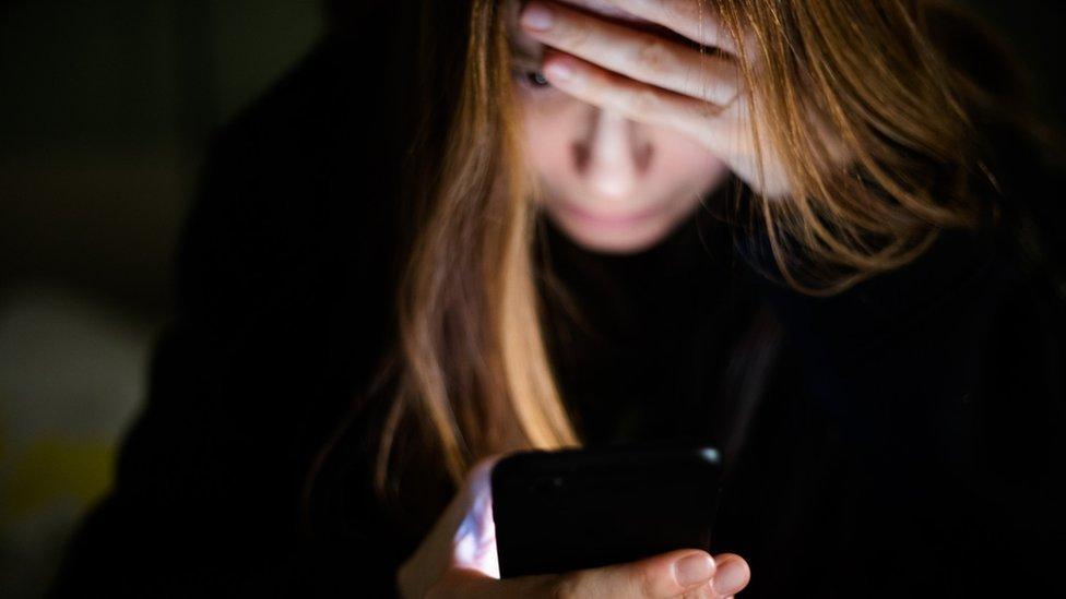 A woman looks at her phone.