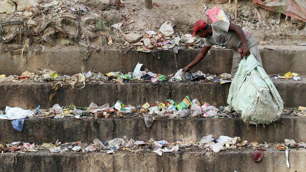 A rag picker collects usable plastics from the garbage