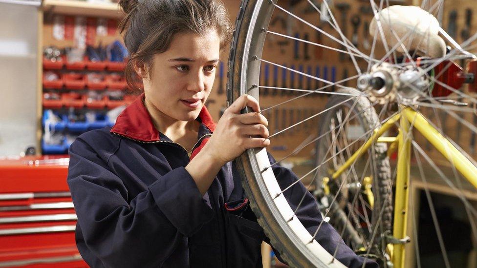 A young woman fixing a bike