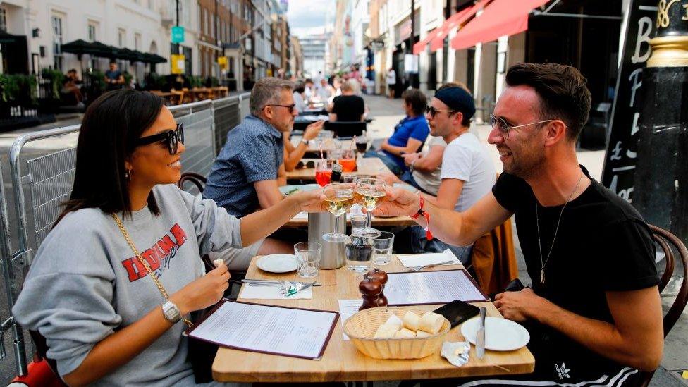 Diners sitting outside toasting with a glass of wine