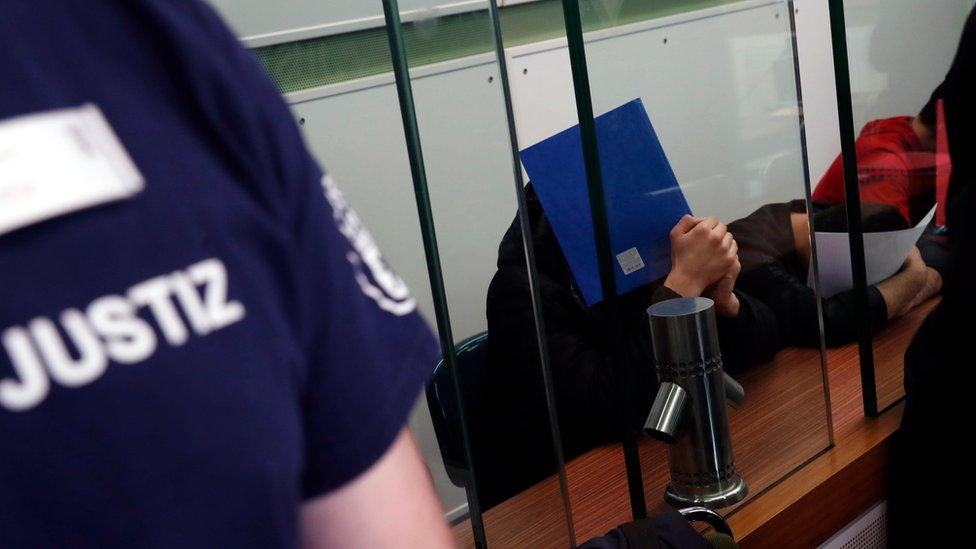 Young men accused of setting alight a homeless man last year cover their faces at the beginning of a trial in Berlin, Germany, on Tuesday