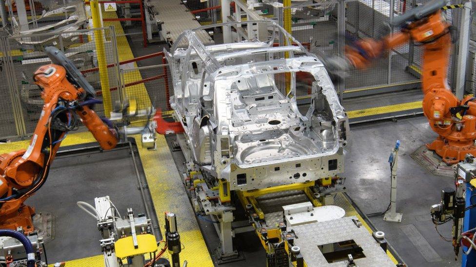 Robotic systems work on the chassis of a car during an automated stage of production at the Jaguar Land Rover factory