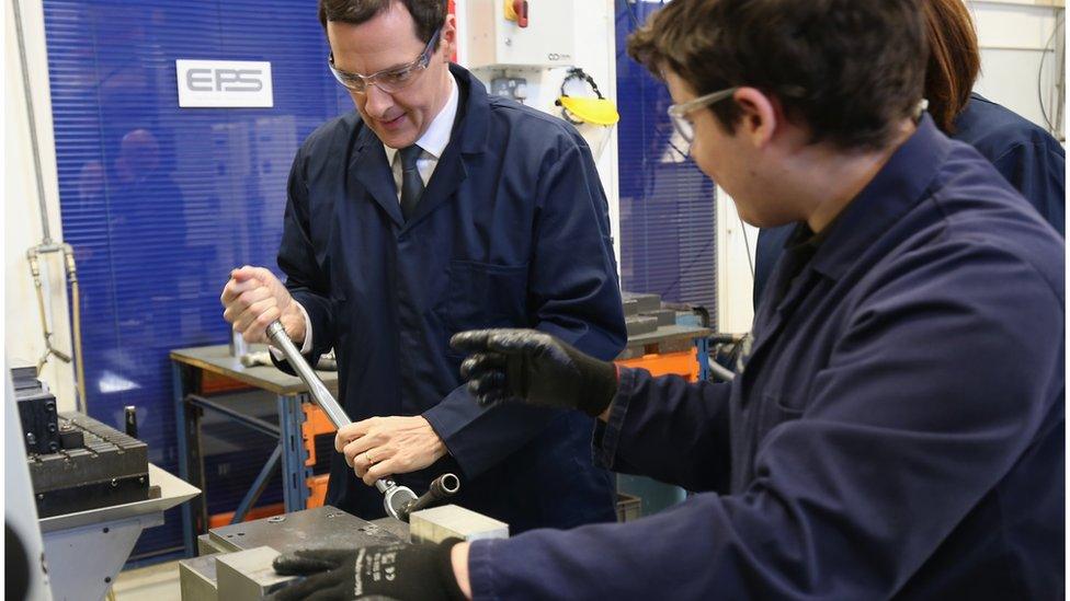 George Osborne uses a wrench with the guidance of apprentice James Spence