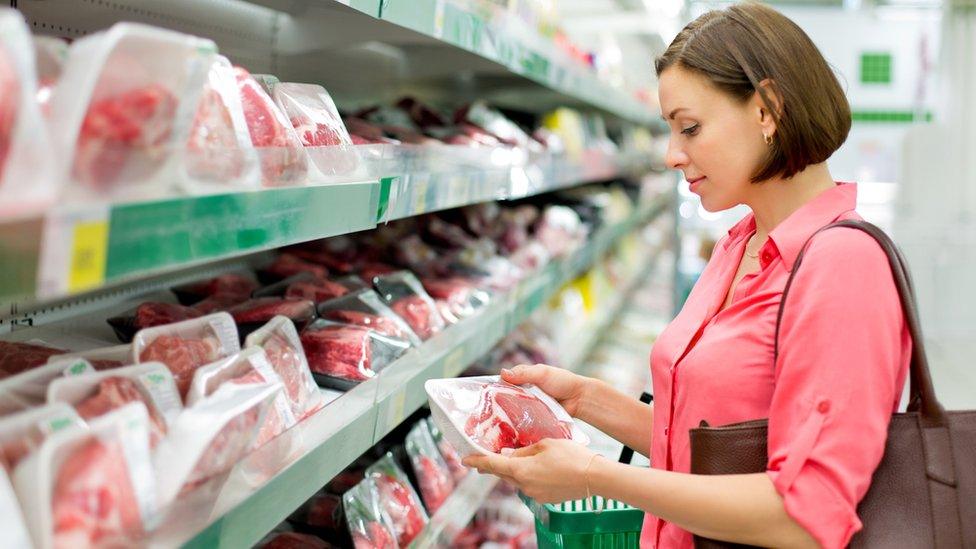 Stock image of woman buying meat in a store