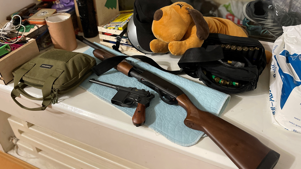 Weapons lie beside a big stuffed toy on a family's window ledge