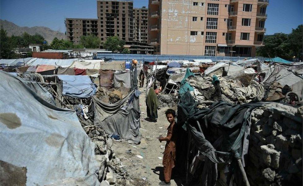 n this photograph taken on June 20, 2016, an internally displaced Afghan child stands beside a shelter at a refugee camp in Kabul.