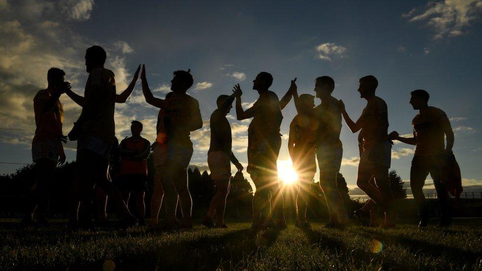 GAA players high-five each other following a match in the sun