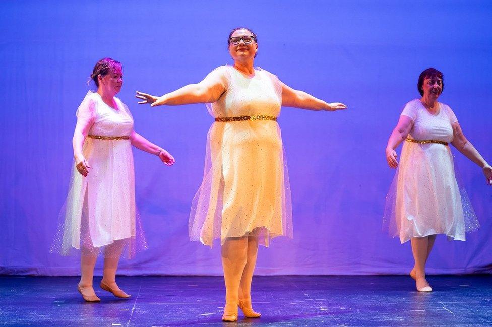 Three women in white dresses do ballet