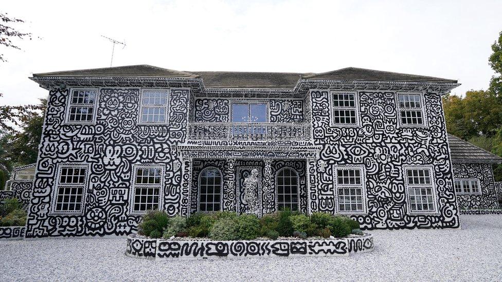 image shows a large white house completely covered in large black doodles