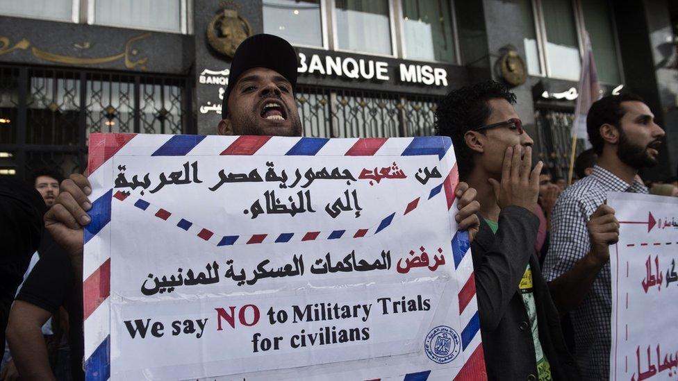 Egyptian protesters hold placards during a protest in Cairo on 26 November 2013