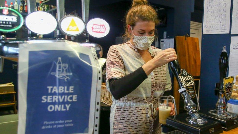 Woman pulling a pint at a pub in Knighton, Powys