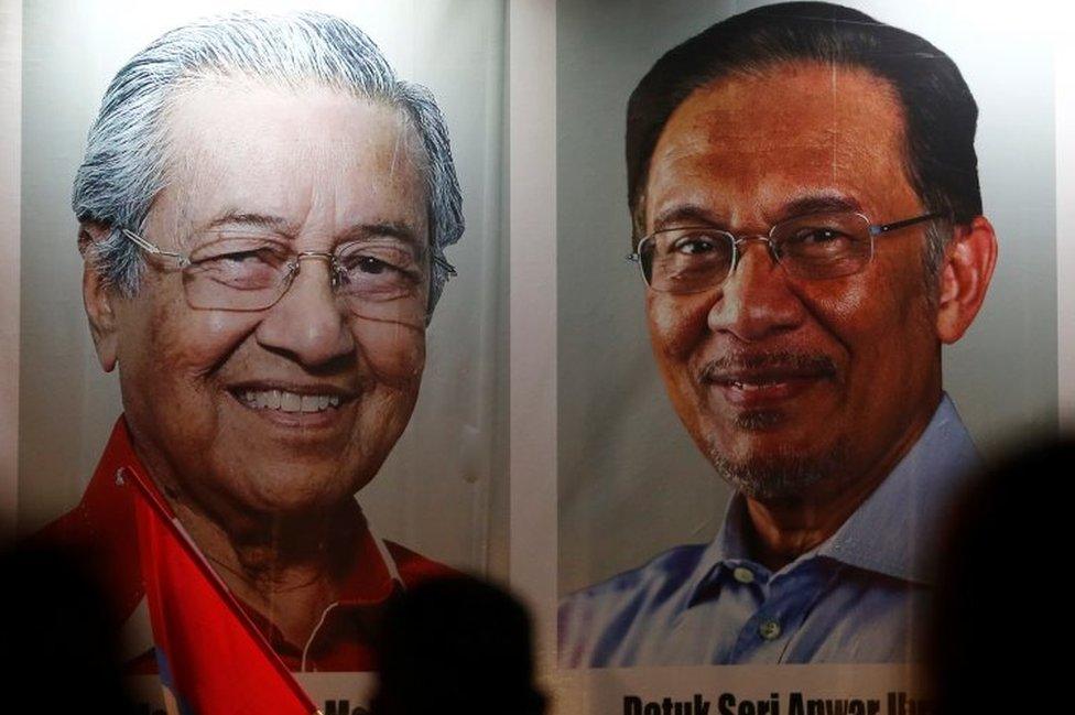 People pass posters of Malaysian Prime Minister Mahathir Mohammad and politician Anwar Ibrahim, who was granted a royal pardon, at a rally in Kuala Lumpur, Malaysia May 16, 2018.