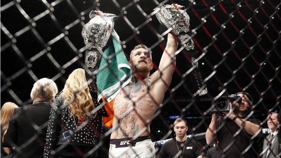 Conor McGregor celebrates with his championship belts