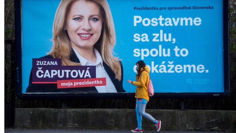 A girl walks past one of Ms Caputova's campaign posters, which reads "Stand up against evil, together we can do it"