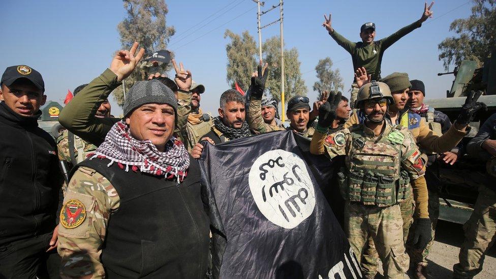 Iraqi soldiers flash victory signs and brandish an IS flag after entering Mosul airport, 23 February