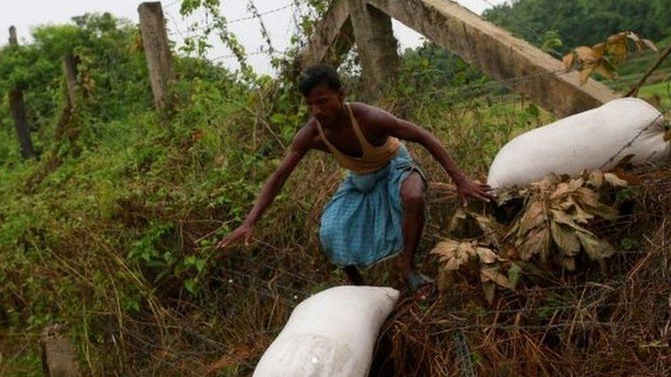 A Rohingya refugee crosses with his belongings over the Bangladesh-Myanmar border fence in Coxâ€™s Bazar, Bangladesh,