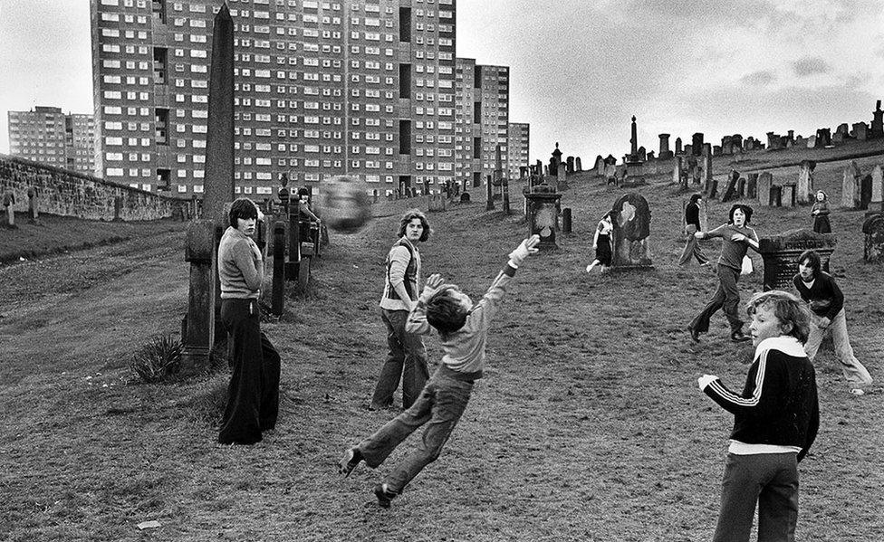 Children playing football, Sighthill Cemetery, Glasgow. Playing amoung the gravestones with high rise tower blocks behind, August 10, 1980