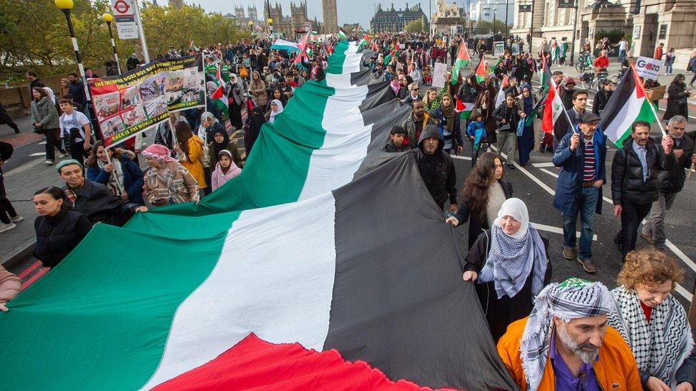 Palestinian flag is carried as people protest during a National March for Palestine organized by the Palestine Solidarity Campaign in London on 28 October 2023