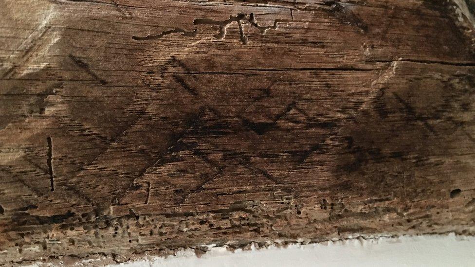 Dark wooden beam carved with upside down Vs