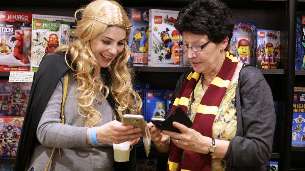 People dressed in Harry Potter gear look at their phones with excitement.