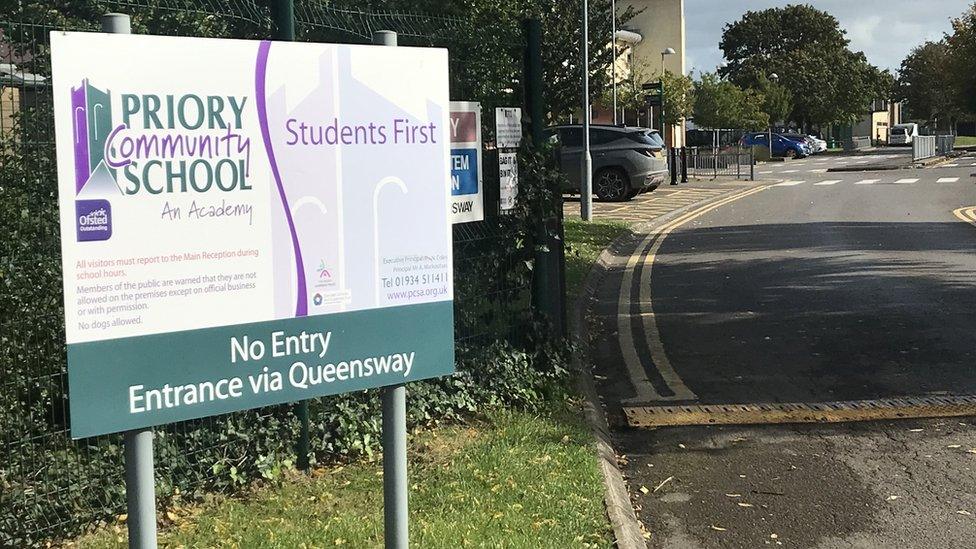 A Priory Community School sign by a road