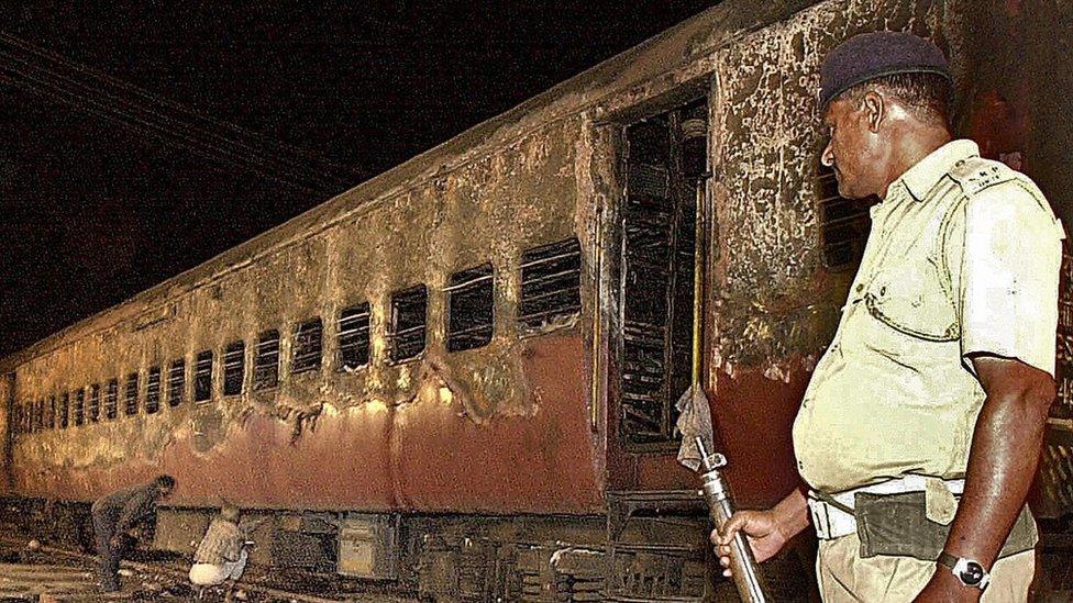 An Indian policeman looks at the charred passenger train in Godhra