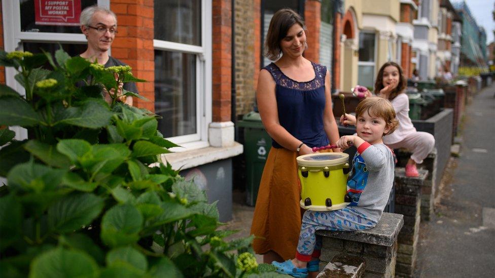 A family applaud and bang drums outside their home