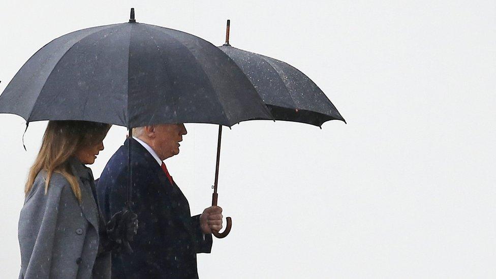 Donald and Melania Trump are pictured under umbrellas walking to the Armistice Ceremony at the Arc de Triomphe, Paris