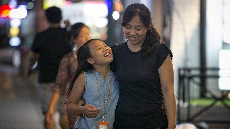 Lee Tae-rim, 10 (L), and her mother, Kim Min-jeong (R), smile as they walk back home from the dance school at night on August 10, 2016 in Seoul,