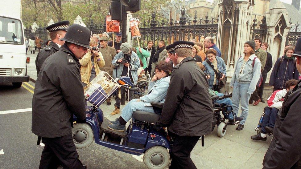 A protestor is removed from outside parliament