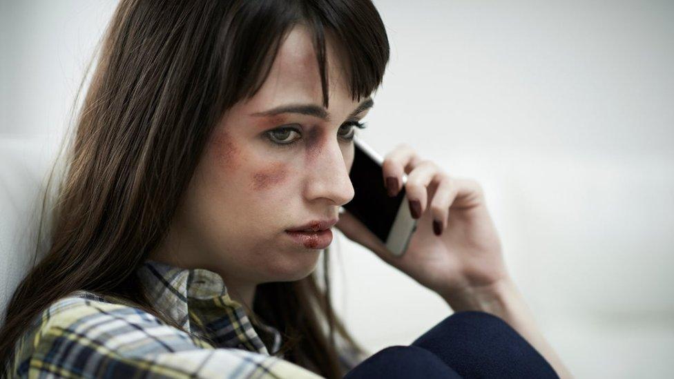 File photo of abused woman phoning helpline.