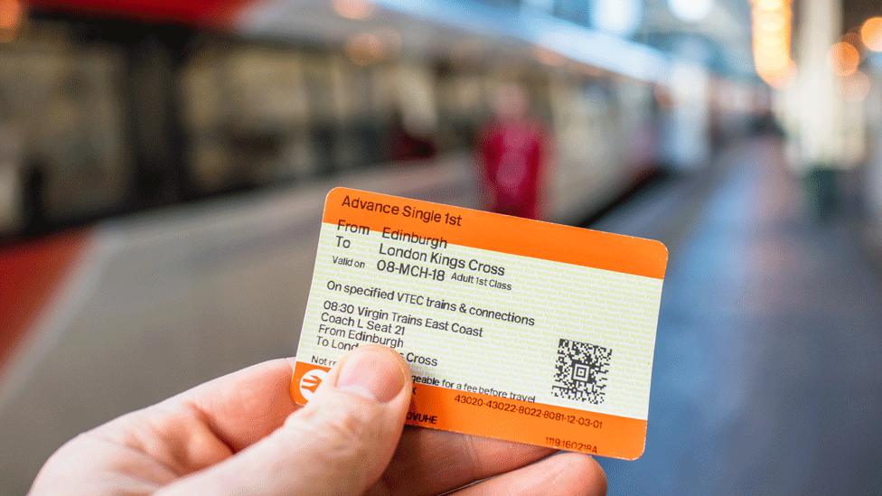 A person holding up a train ticket with train in background