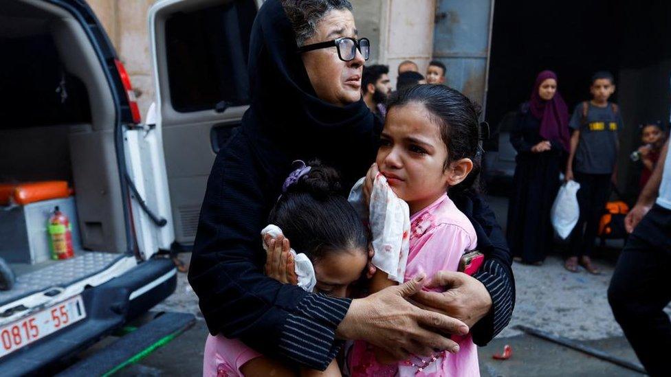 woman and children react after strike in Khan Younis