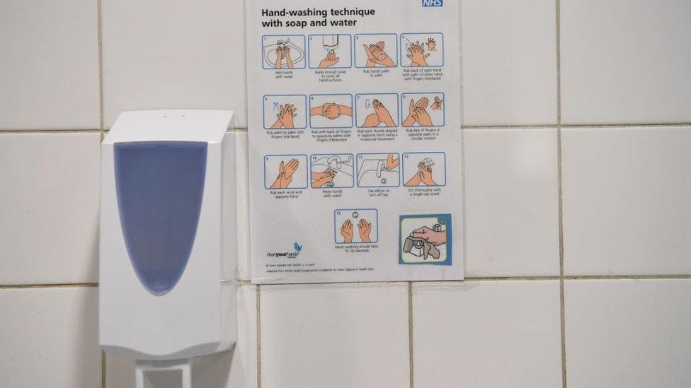 An NHS sign depicting how to wash your hands is on display in a public toilet