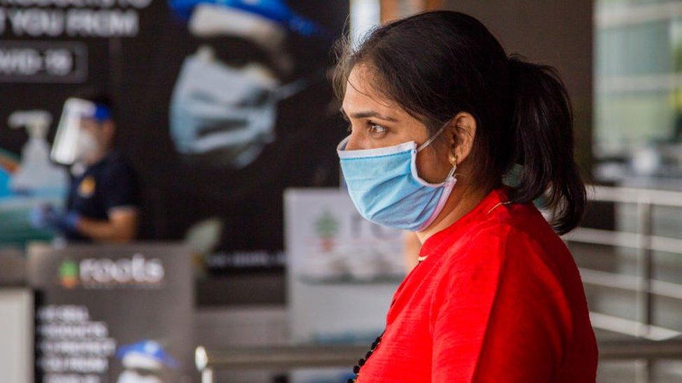 An Indian taveller wearing a protective mask waits at the drop-off point of Terminal 3 of the Indira Gandhi International Airport, as the country relaxed its lockdown restriction on May 26, 2020 in Delhi, India.