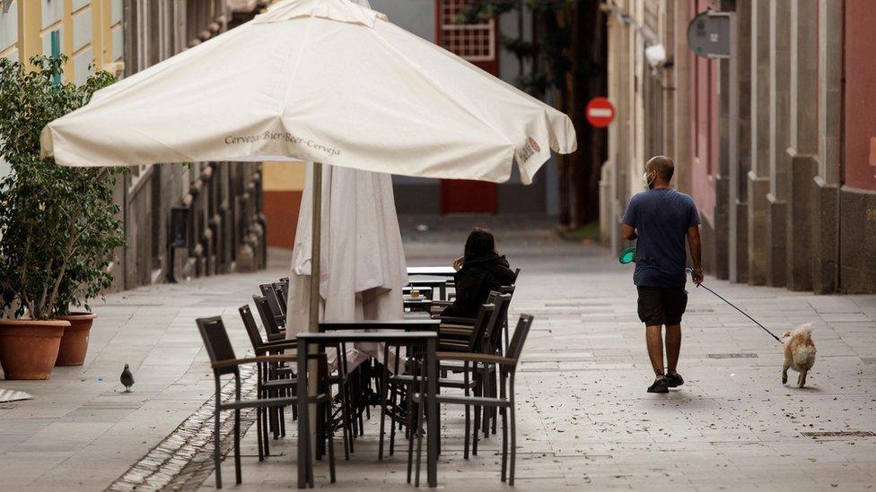 A man walks his dog along a street in Santa Cruz de Tenerife, Canary Islands, Spain