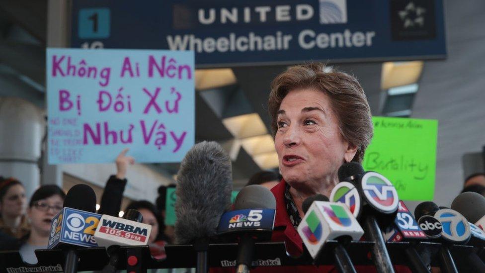 Congresswoman Jan Schakowsky speaks in front of a protester's sign, written in Vietnamese