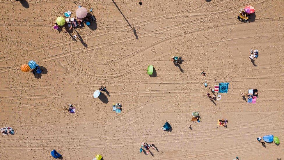 An aerial photo of the first beach-goers on the beach of Scheveningen in the Netherlands