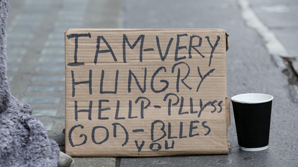 A sign reads: "I AM - VERY HUNGRY - HELP PLLYSS GOD BLESS YOU"