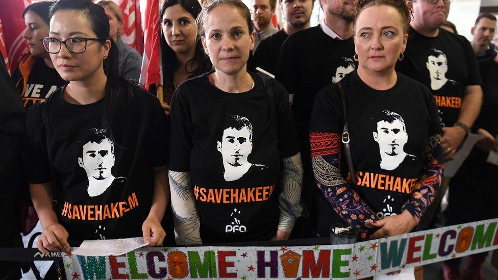 Supporters at the airport hold up 'Welcome Home' signs